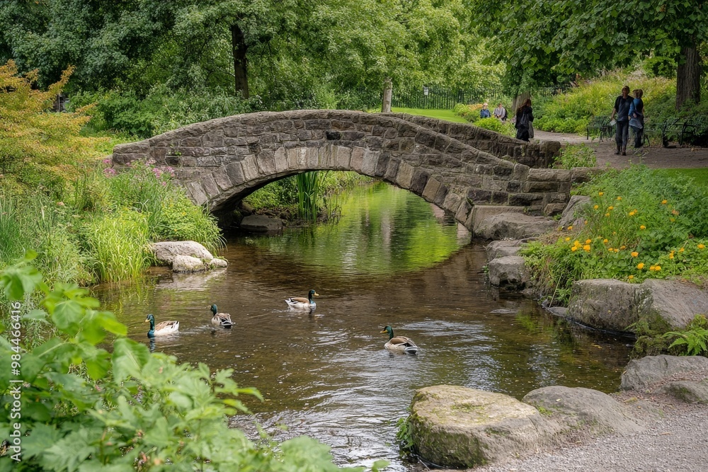 A tranquil scene of a stone bridge arching over a gentle stream with ducks swimming. Lush green foliage surrounds the area, creating a peaceful, natural setting. A tranquil scene of a stone bridge arching over a gentle stream with ducks swimming. Lush green foliage surrounds the area, creating a peaceful, natural setting.