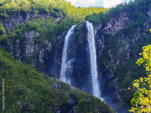 The waterfall against the backdrop of a majestic mountain fascinates with its beauty, creating an atmosphere of tranquility and the power of nature
