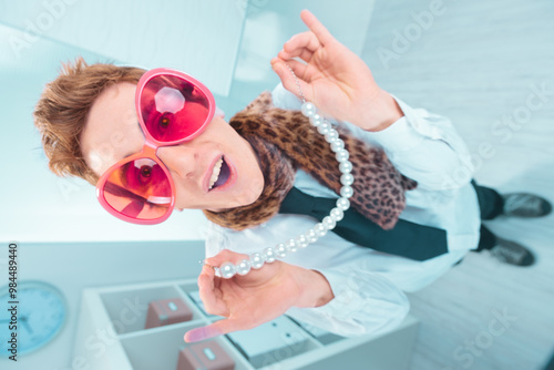 Businessman with pink heart shaped glasses showing pearl necklac photo