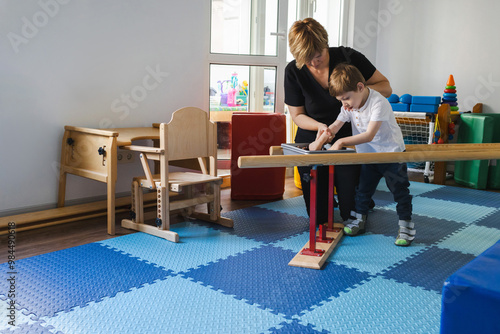 Cuadro en lienzo Handsome little boy with cerebral palsy practices walking using handrails with s