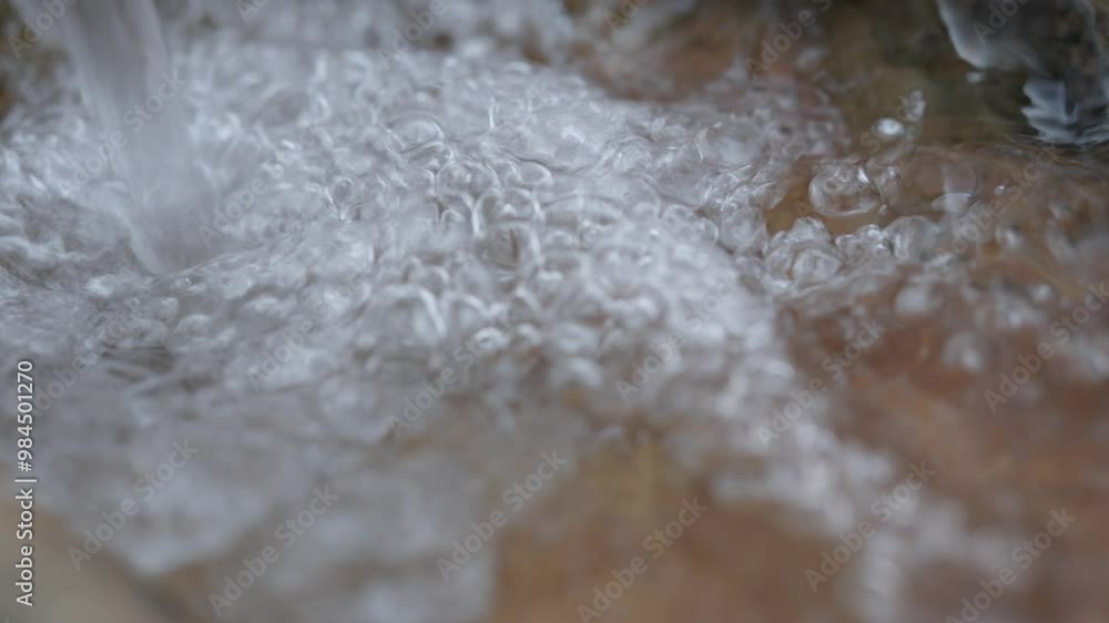 Close up to water falling from a waterfall in slow motion in a stream, bubbling water, clear water
Close up to water falling from a waterfall in slow motion in a stream, bubbling water, clear water