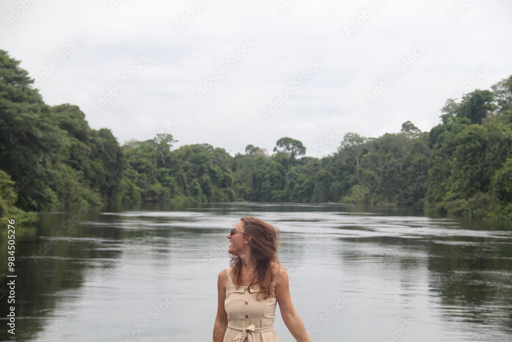 mulher com vestido claro e chapéu na beira de rio em hotel de selva em alta floresta, mato grosso mulher com vestido claro e chapéu na beira de rio em hotel de selva em alta floresta, mato grosso