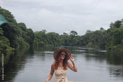 mulher com vestido claro e chapéu na beira de rio em hotel de selva em alta floresta, mato grosso  photo