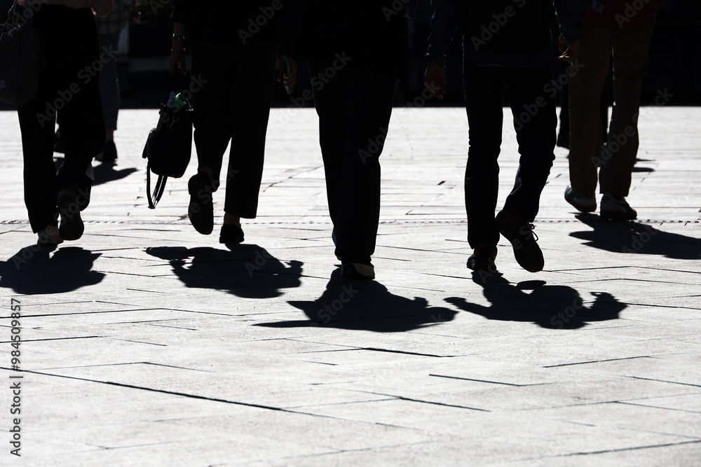 Obraz premium Black silhouettes and shadows of people on the street. Crowd walking down on sidewalk, concept of pedestrians, crime, society, city life