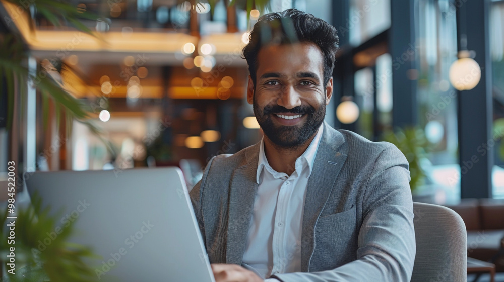 Smiling businessman working on laptop in modern office lobby space. Young student using computer remote studying, watching online webinar, zoom virtual training on video call meeting. Smiling businessman working on laptop in modern office lobby space. Young student using computer remote studying, watching online webinar, zoom virtual training on video call meeting.