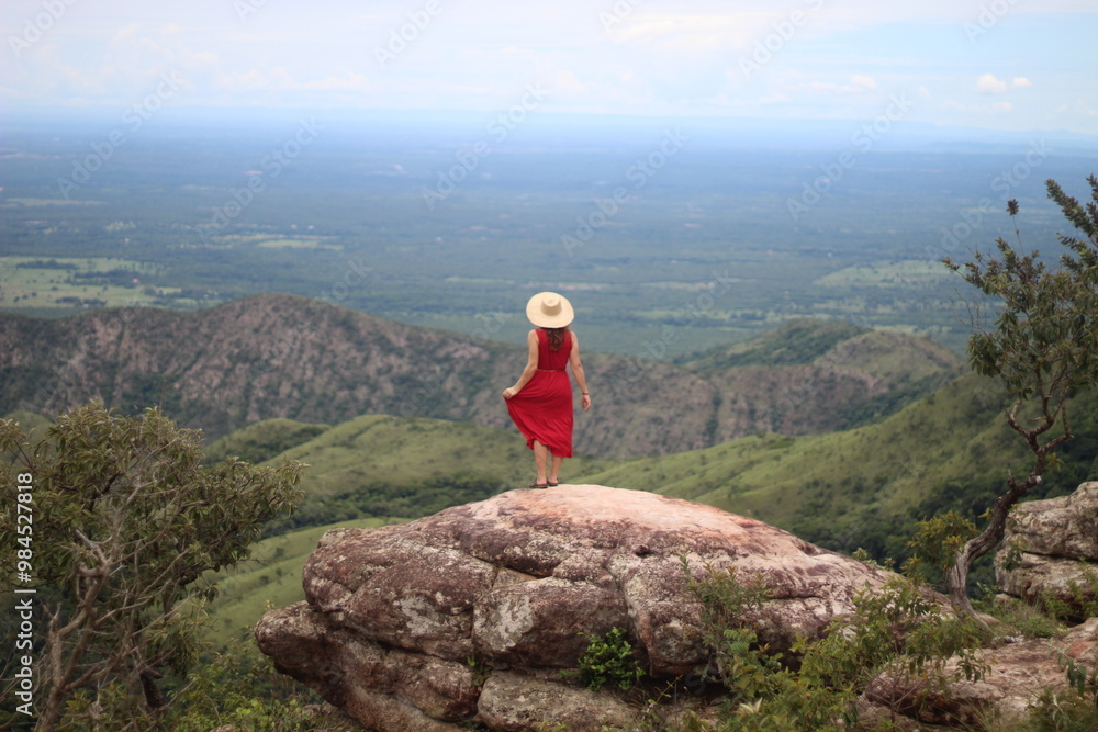 Fototapeta premium mulher de vestido vermelho e chapéu no mirante Alto do Céu, na Chapada dos Guimarães, Mato Grosso 