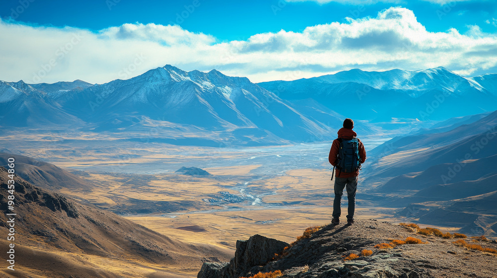 Fototapeta premium A traveler standing at the edge of a high Tibetan plateau, taking in the breathtaking view of the surrounding mountains and valleys