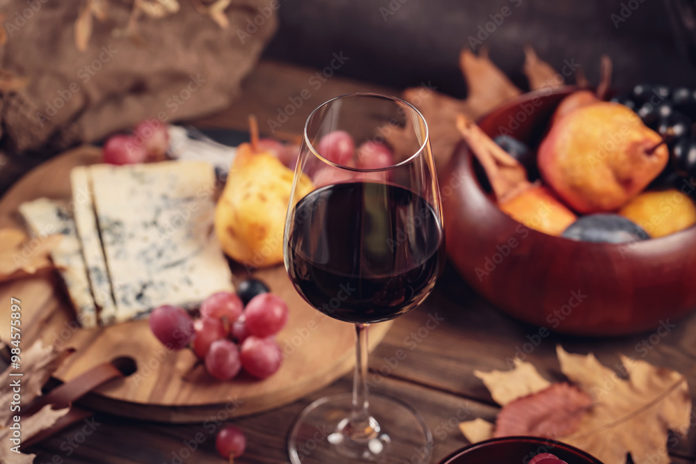 Glass of red wine served with blue cheese on dark wooden background. Autumn picnic with wine and cheese platter, fruits and dry leaves in rustic style Glass of red wine served with blue cheese on dark wooden background. Autumn picnic with wine and cheese platter, fruits and dry leaves in rustic style