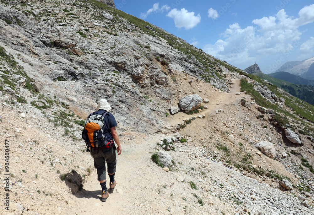 hiker with backpack and hiking boots walking on trail in Dolomites mountains in Italian Alps hiker with backpack and hiking boots walking on trail in Dolomites mountains in Italian Alps