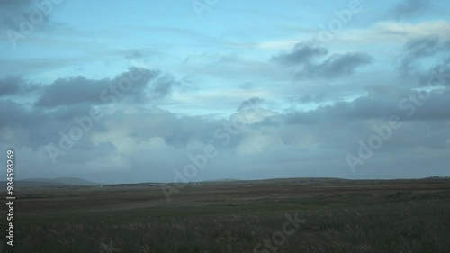 4K Time-Lapse of moving clouds over field at sunset. The Isle of North Uist, Scotland