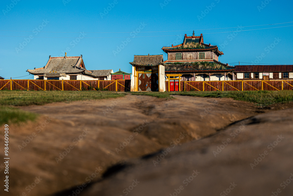 Fototapeta premium mongolian monastery at sunrise with country road in the foreground