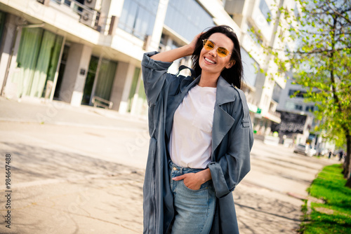 Photo of shiny attractive lady dressed grey coat dark eyewear smiling enjoying good weather outdoors town street