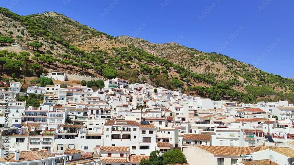 Panoramic view of typical andalusian white village Mijas located on the Costa del Sol, Spain. A lot of white washed houses, mountains and pine forest in the background. Sunny weather, blue sky. Panoramic view of typical andalusian white village Mijas located on the Costa del Sol, Spain. A lot of white washed houses, mountains and pine forest in the background. Sunny weather, blue sky.
