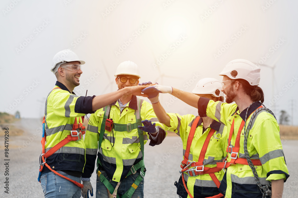 Group of male engineer standing putting their hands together at wind turbines farm, planing maintenance of wind turbines Group of male engineer standing putting their hands together at wind turbines farm, planing maintenance of wind turbines