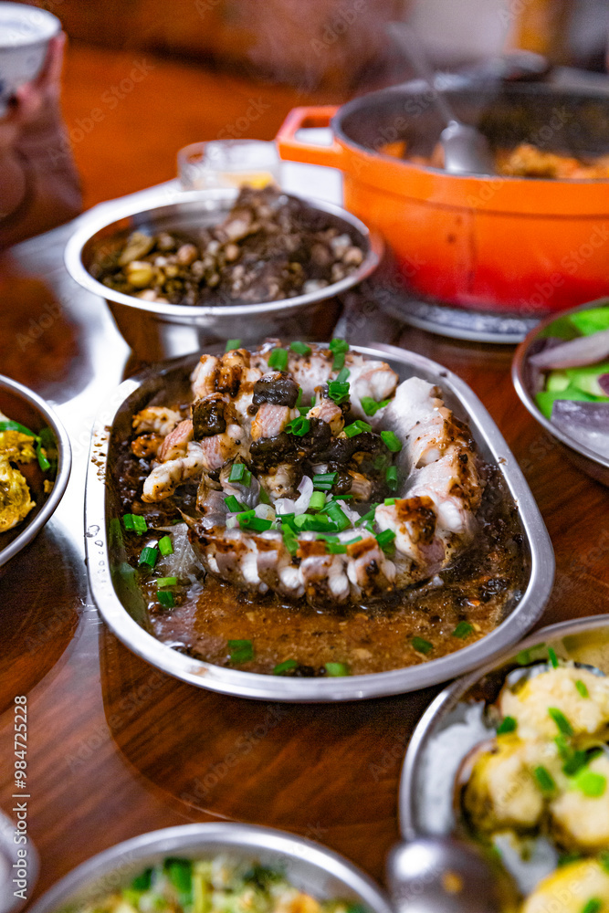 Cantonese-style steamed eel with black bean sauce served on a metal dish, topped with scallions and paired with savory sauces Cantonese-style steamed eel with black bean sauce served on a metal dish, topped with scallions and paired with savory sauces