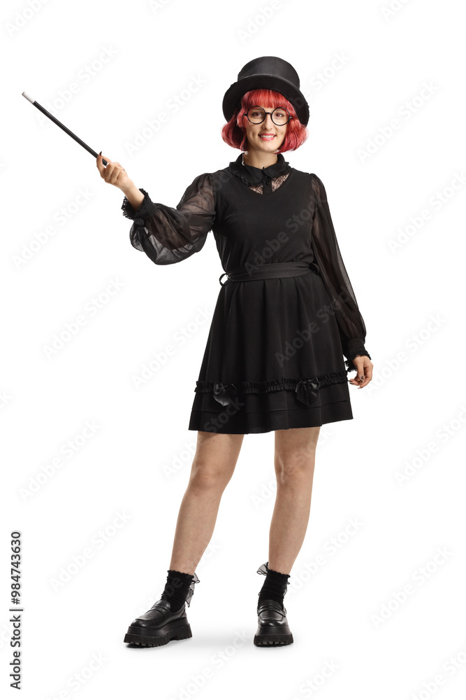 Full length portrait of a female magician with a top hat and black dress holding a magic wand Full length portrait of a female magician with a top hat and black dress holding a magic wand