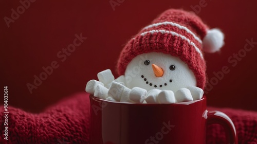 A cheerful snowman nestled in a red mug surrounded by marshmallows during win...