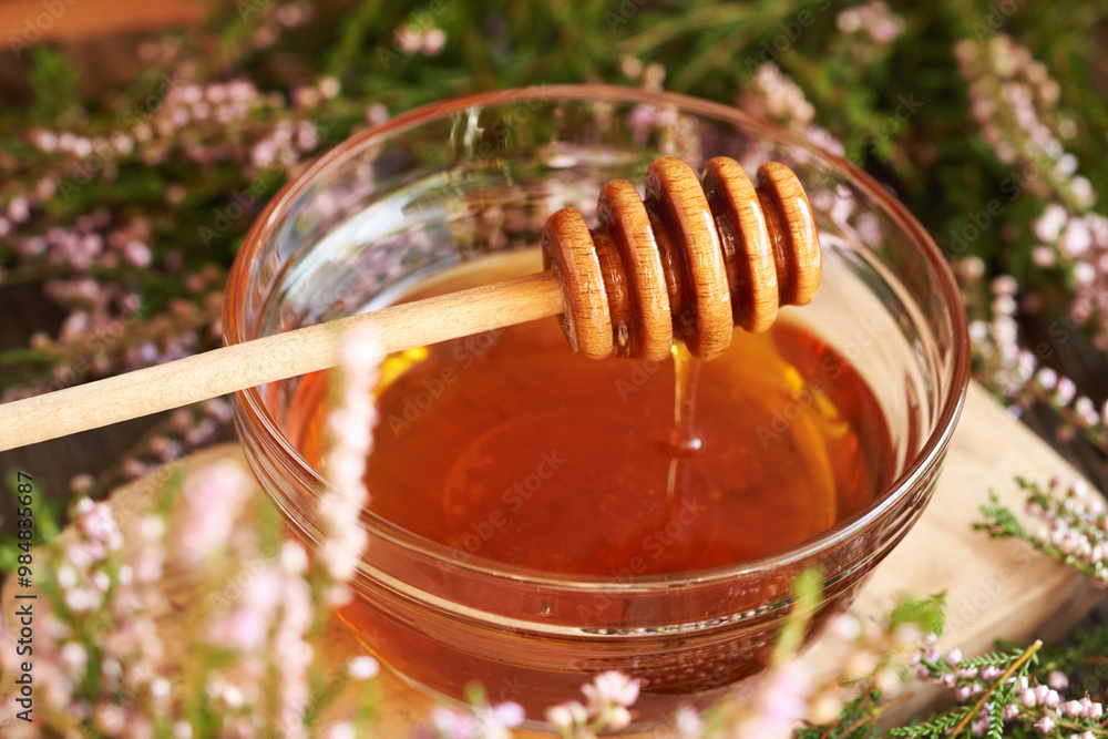 Herbal syrup in a glass bowl with wild heather flowers harvested in the forest and a honey dipper Herbal syrup in a glass bowl with wild heather flowers harvested in the forest and a honey dipper