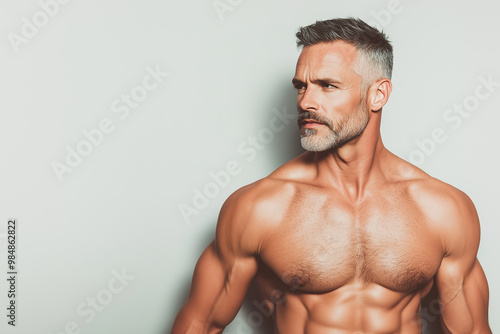Fabulous at any age. Portrait of charismatic muscular 50 years old man standing over light gray background. Perfect haircut and body. Copy-space. Studio shot