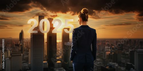 Back view of a woman in a suit looking at big 2025 numbers on the city skyline from the rooftop of a building at sunset, symbolizing a successful business concept.