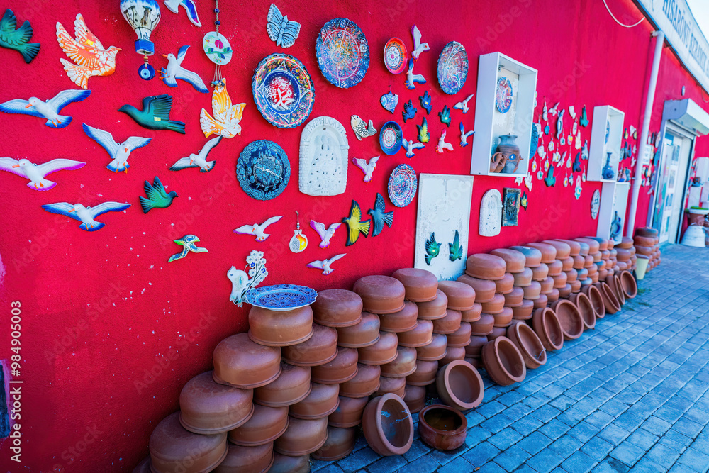 A vibrant collection of colorful ceramic art, decorative plates, and pottery on a striking red background, showcasing artistic creativity and vivid design.
