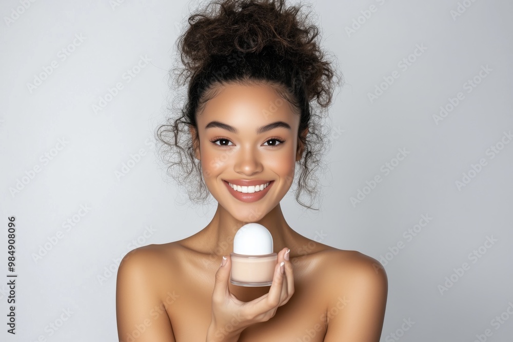 A woman is holding a bottle of makeup in her hand. She is smiling and she is happy. A woman is holding a bottle of makeup in her hand. She is smiling and she is happy.