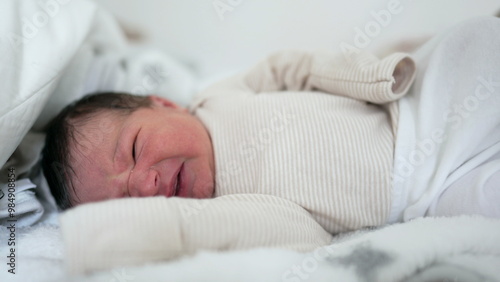 Newborn baby lying in bed, stretching and making a slight grimace, a raw and tender moment of infancy. close-up emphasizes the delicate features and vulnerability of a newborn