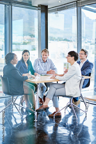 Team, meeting and paper in office for business, marketing strategy and finance management. Corporate people, woman speaker and discussion at table with report, feedback or planning for upcoming audit photo