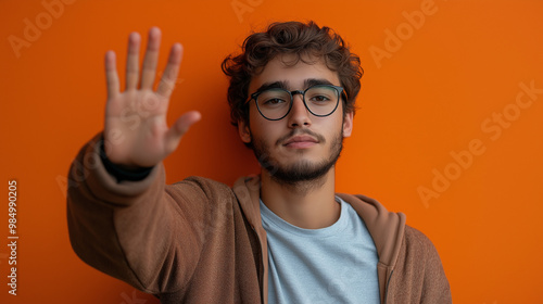 on the right side male student on a single colour background raching his hand. fisheye photo