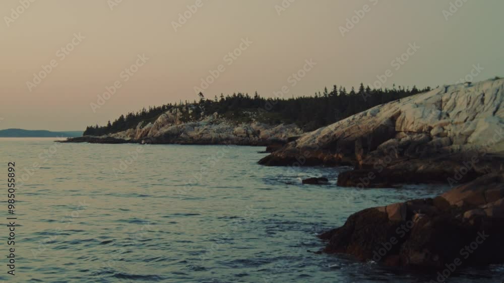 A stunning view of the rocky shoreline bathed in the soft glow of twilight, as the calm ocean waves gently lap against the coast of Nova Scotia. A stunning view of the rocky shoreline bathed in the soft glow of twilight, as the calm ocean waves gently lap against the coast of Nova Scotia.