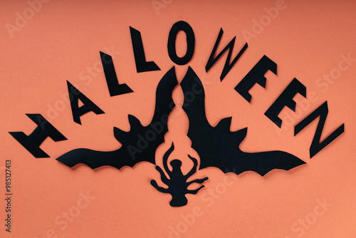 Black Paper Cutouts of Bats, Spiders and Text Halloween on Orange Background for Happy Halloween photo