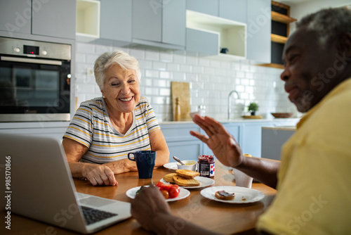 Diverse senior couple eating breakfast together on the kitchen table