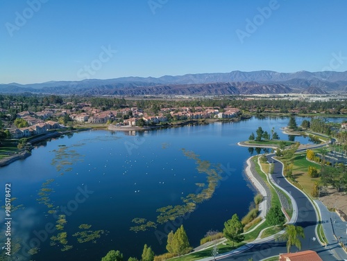 Aerial shot of Harveston Lake Park in Temecula, California. Lake and surrounding buildings create scenic landscape. Town architecture is visible from above. Aerial view of lake and cityscape. photo