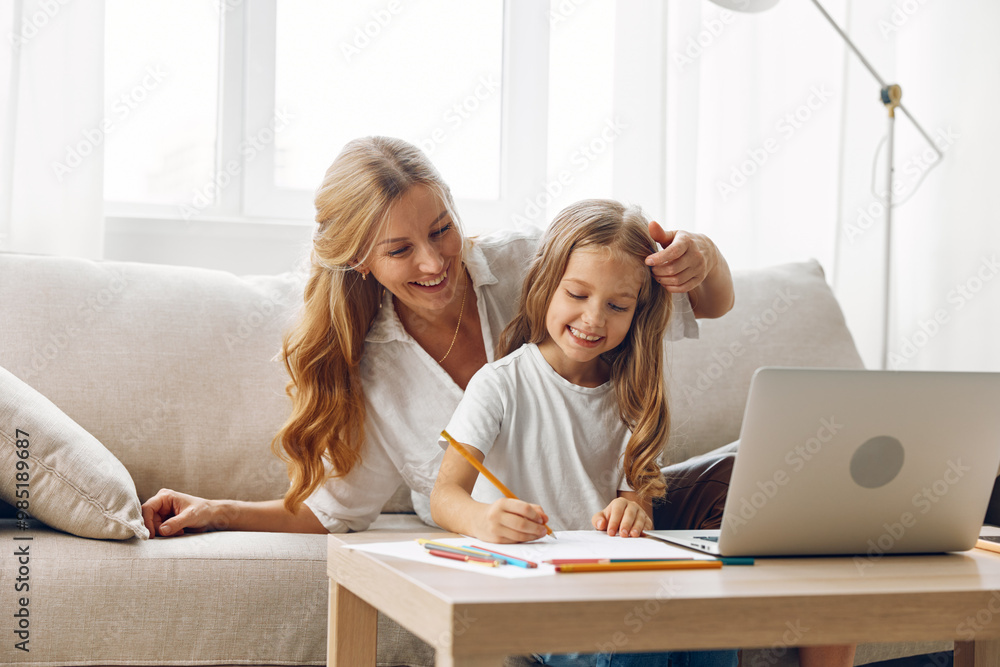 Mother and daughter engaging in online learning and creative drawing activities on the couch with laptop and pencils