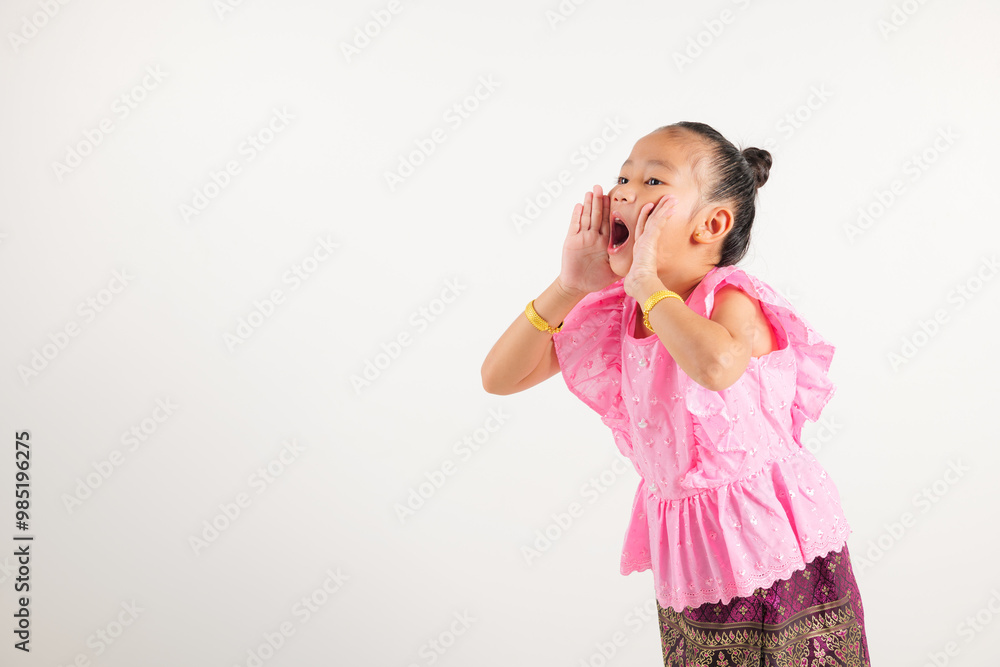 Portrait Thailand kid girl smiling traditional Thai dress costume use hand covering her mouth, studio shot isolated white background, kindergarten engaged in lively conversation, making announcement Portrait Thailand kid girl smiling traditional Thai dress costume use hand covering her mouth, studio shot isolated white background, kindergarten engaged in lively conversation, making announcement