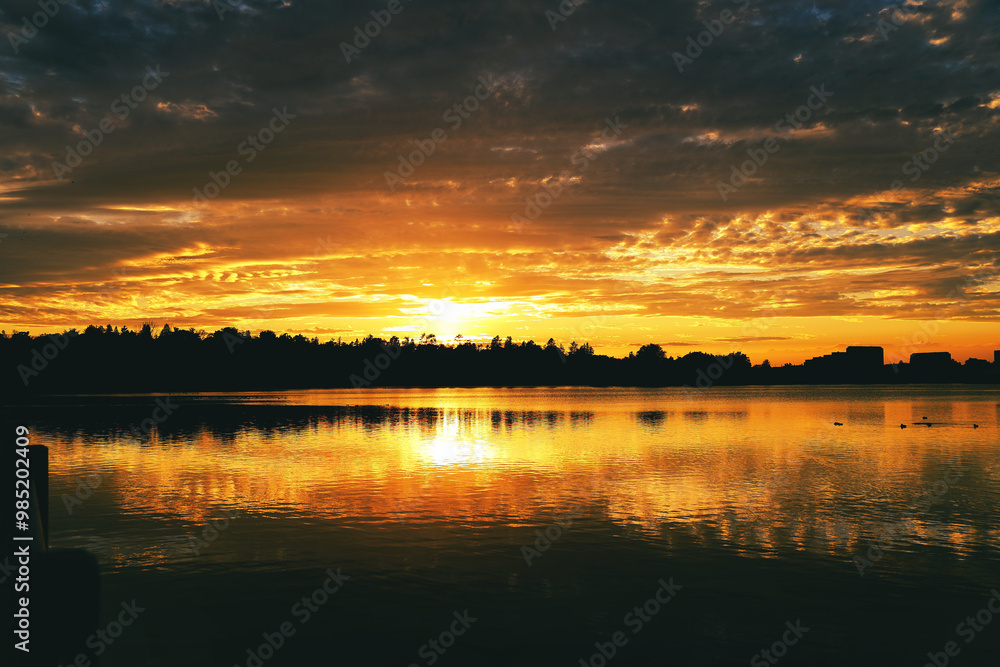 Obraz premium The evening sun turns the beautiful Dows Lake into burnished gold during a fiery twilight sunset on a warm fall evening at Ottawa,Ontario,Canada 