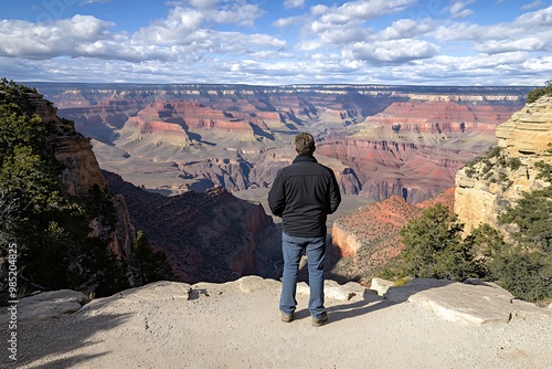 A lone man stands at the edge of the Grand Canyon, taking in the awe-inspiring view. photo