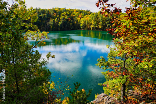 Pink Lake, a meromictic lake at Gatineau Park as seen from a rocky outcrop amidst magnificent red,orange and yellow fall colors during autumn season at Gatineau Park,Quebec,Canada