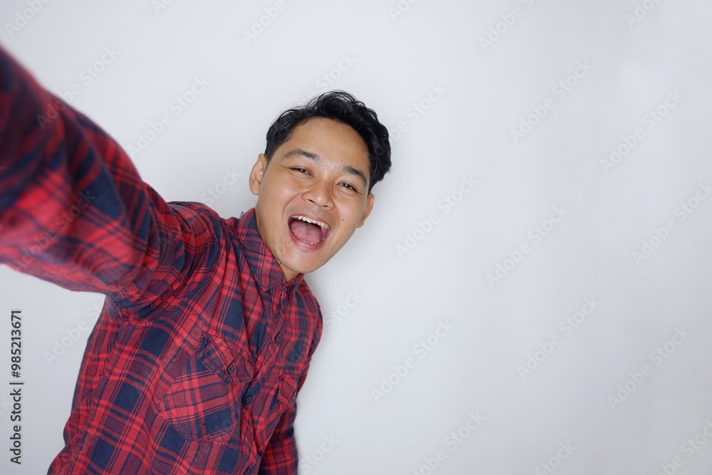 portrait of a handsome Indonesian man having a random expression wearing a checkered red flannel shirt on a white isolated background portrait of a handsome Indonesian man having a random expression wearing a checkered red flannel shirt on a white isolated background