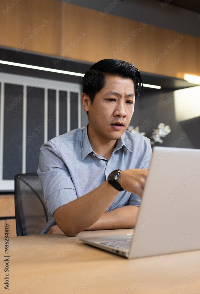 Working on laptop, asian man in office focusing on business tasks Working on laptop, asian man in office focusing on business tasks