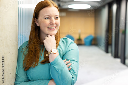 Smiling woman in business attire standing in modern office hallway