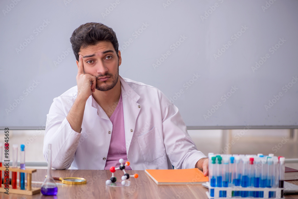 Young male chemistry teacher sitting in the classroom Young male chemistry teacher sitting in the classroom