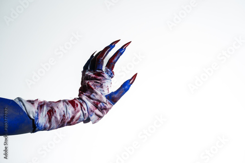 Tableau sur toile A blue witch hand with red nails, wrapped in a blood-stained bandage against a white background