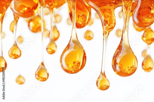 Golden liquid drops falling on white background.