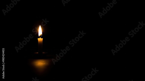 A solitary candle flickers in darkness, casting a warm glow and creating a serene ambiance.