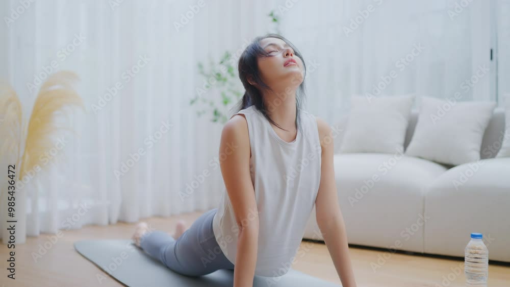 Young Asian woman stretching yoga workout on exercise mat while online training class with computer laptop in living room Young Asian woman stretching yoga workout on exercise mat while online training class with computer laptop in living room