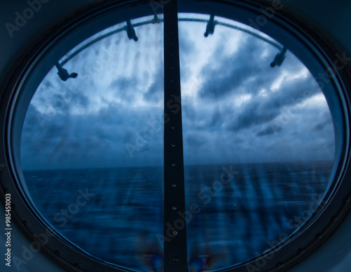 view of the ocean on a dark cloudy day from a porthole window on a cruise ship
