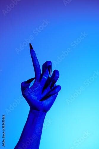 Photography A blue witch hand with sharp red nails, set against a backdrop of blue fire