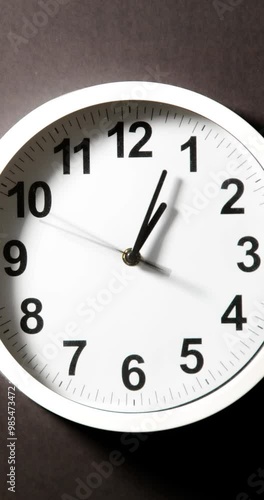 Close up to wall clock, with running time pointer. Sun and sky reflecting on clock face time passing by. Vertical time lapse on a modern white Clock on blur background. Wall clock show running time. 