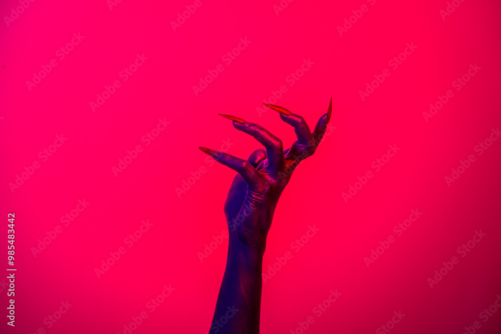 Fototapeta premium A witch hand with long nails appears against a red fire background, evoking a demonic, monstrous presence. Blending vampire, alien, ghost, and zombie elements, it perfectly embodies Halloween